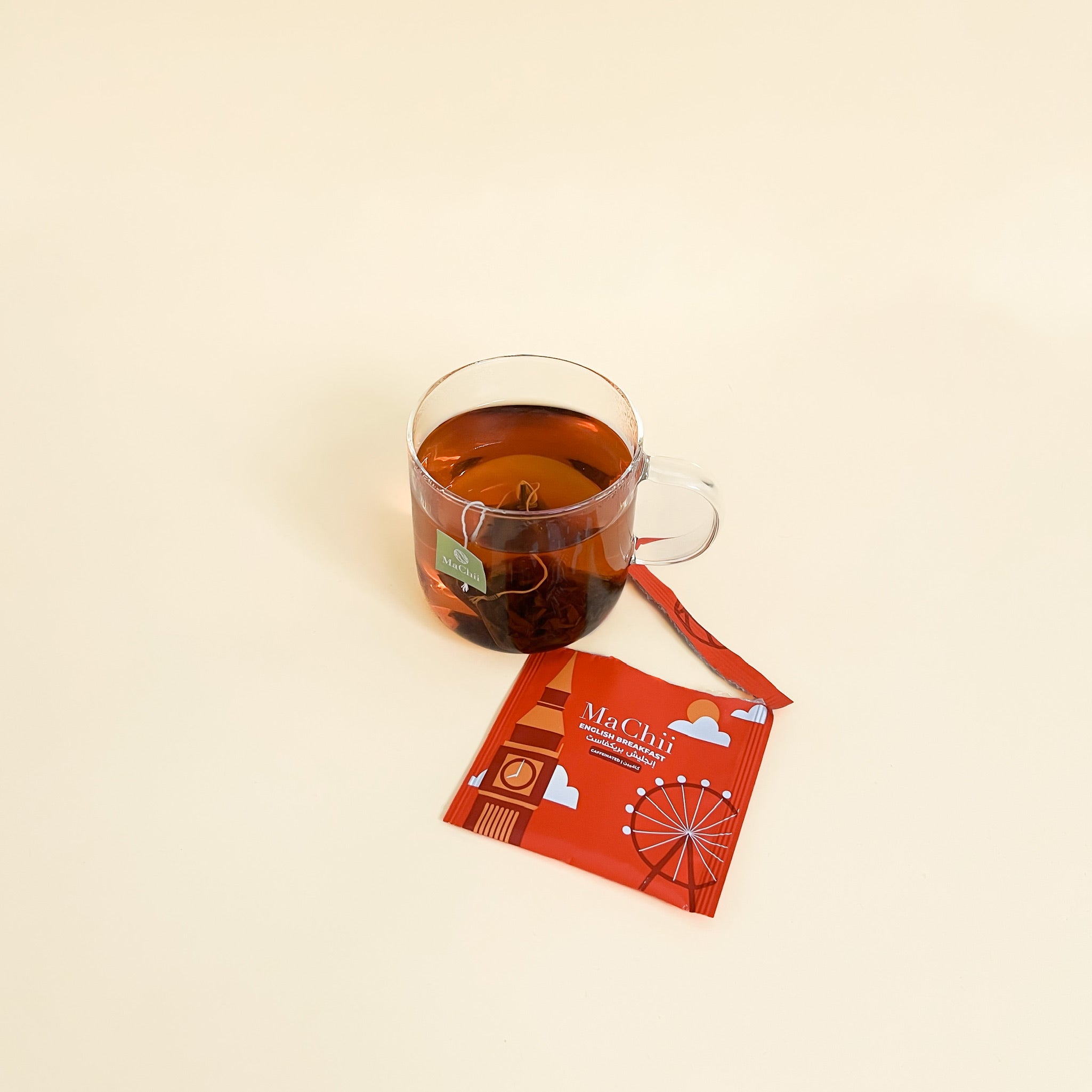 English breakfast organic whoelsale tea brewing in a cup with a tea bag to the side of the cup. the packaging is open next to the glass mug