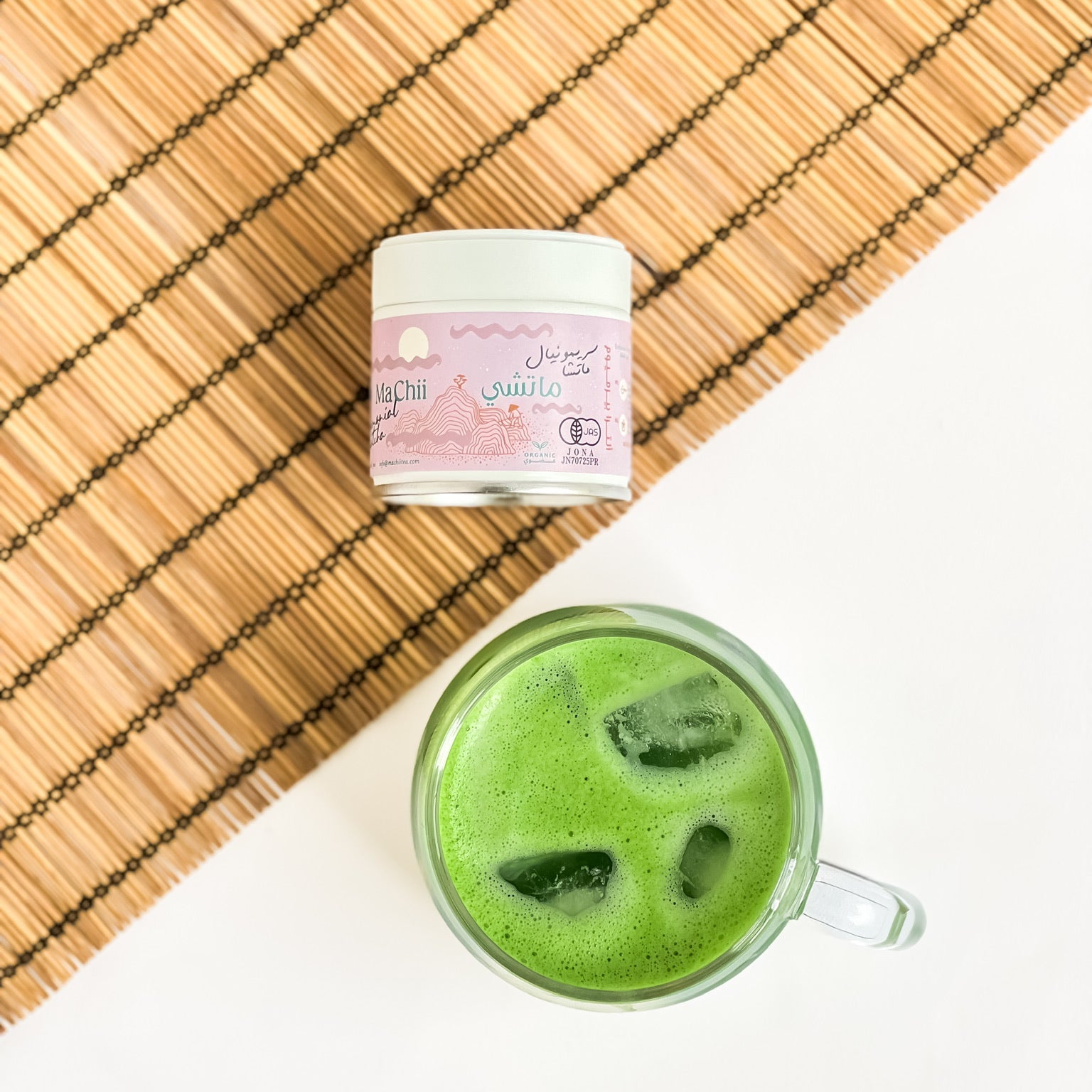 ceremonial matcha organic pink tin next to a cup of iced matcha.