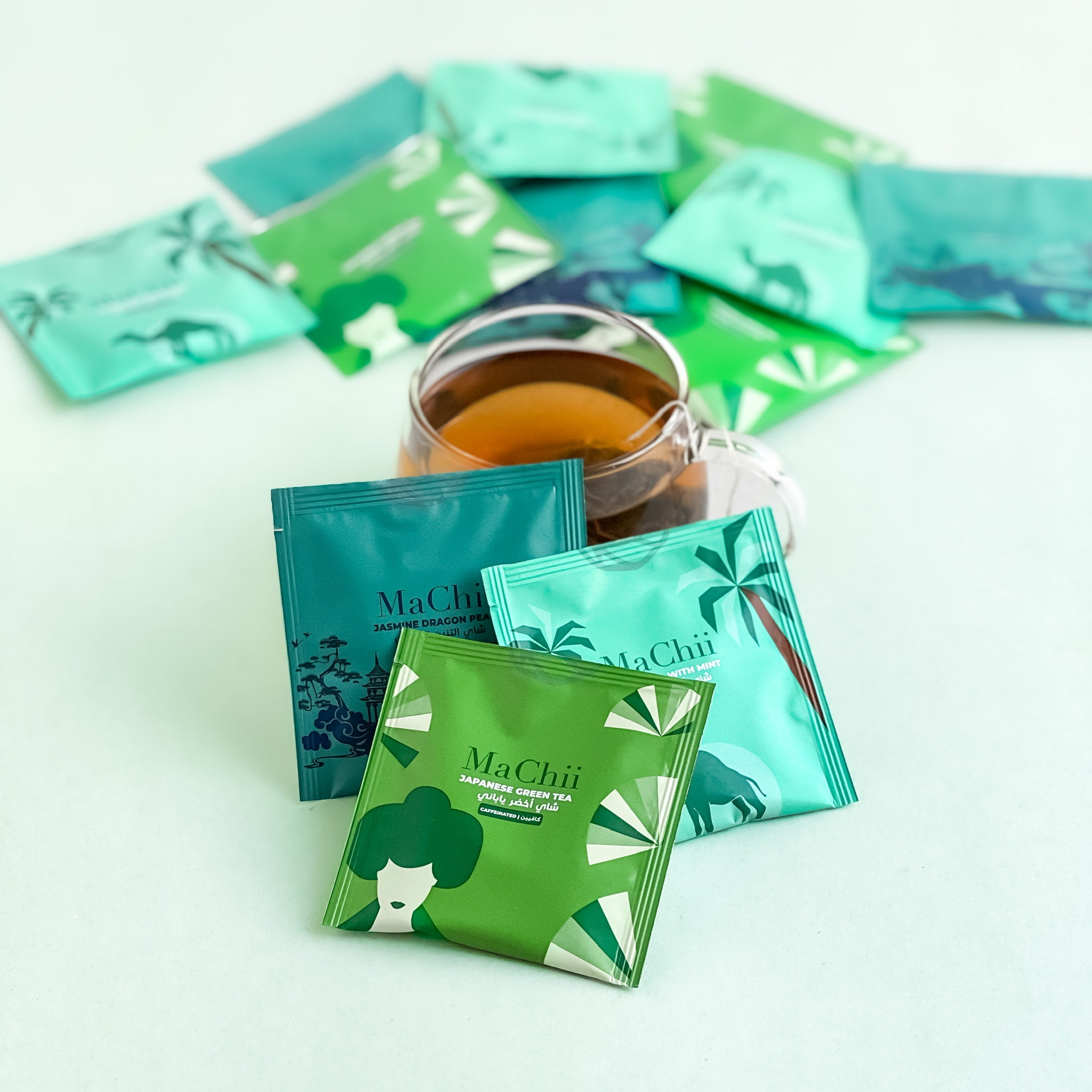 a green tea collection from china and Japan. it includes Japanese sencha green tea, jasmine dragon pearl and a gunpowder green tea with mint. the organic tea is brewing in a glass cup.