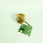 Japanese sencha green tea bag brewing in a cup next to an envelope package