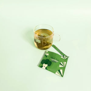 
                  
                    Japanese sencha green tea bag brewing in a cup next to an envelope package
                  
                