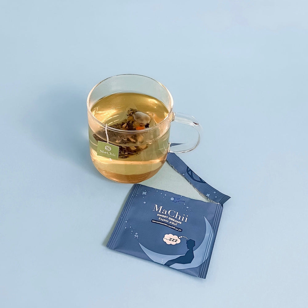 
                  
                    sweet dreams herbal blend chamomile in tea silk biodegradable tea bag on top of an envelope package with a picture of a sleeping man on a moon at night. the tea bag is brewing in a cup and is yellow
                  
                