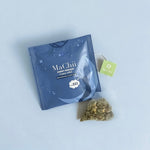 sweet dreams herbal blend chamomile in tea silk biodegradable tea bag on top of an envelope package with a picture of a sleeping man on a moon at night