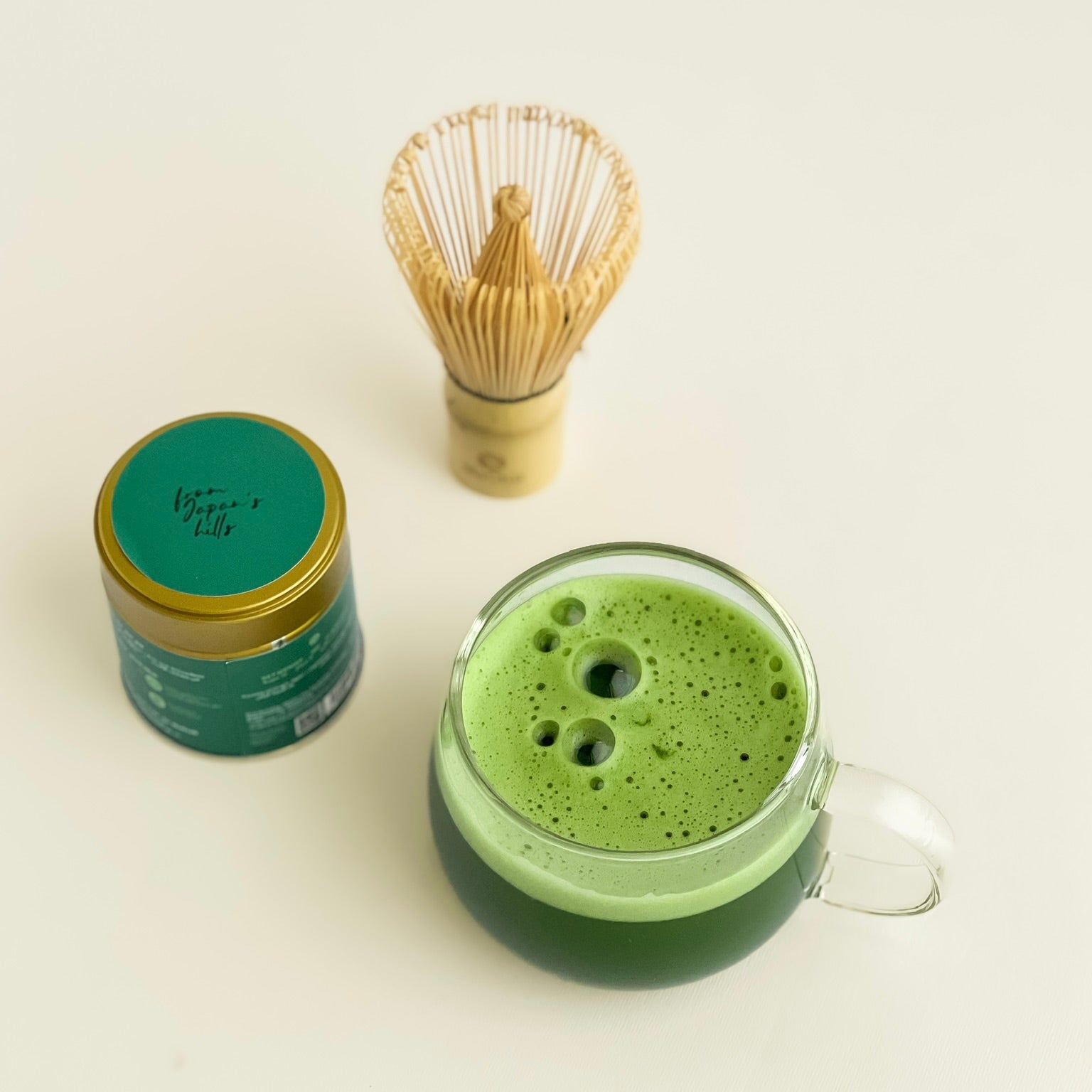 organic ceremonial matcha prepared in a glass cup with a bamboo matcha whisk. 