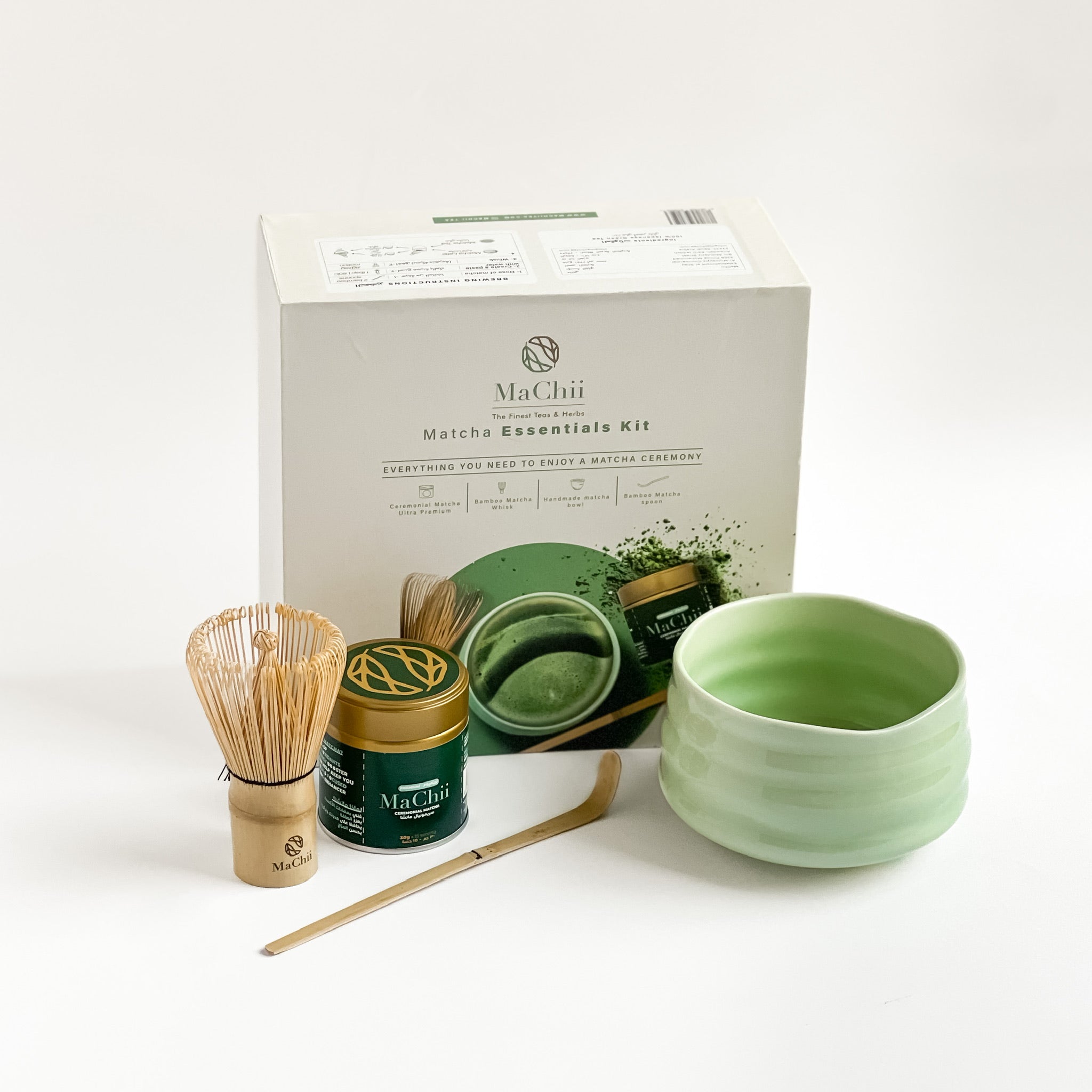a matcha gift box with a gold organic ceremonial matcha tin, a bamboo whisk, a bamboo spoon and a green ceramic matcha bowl. 