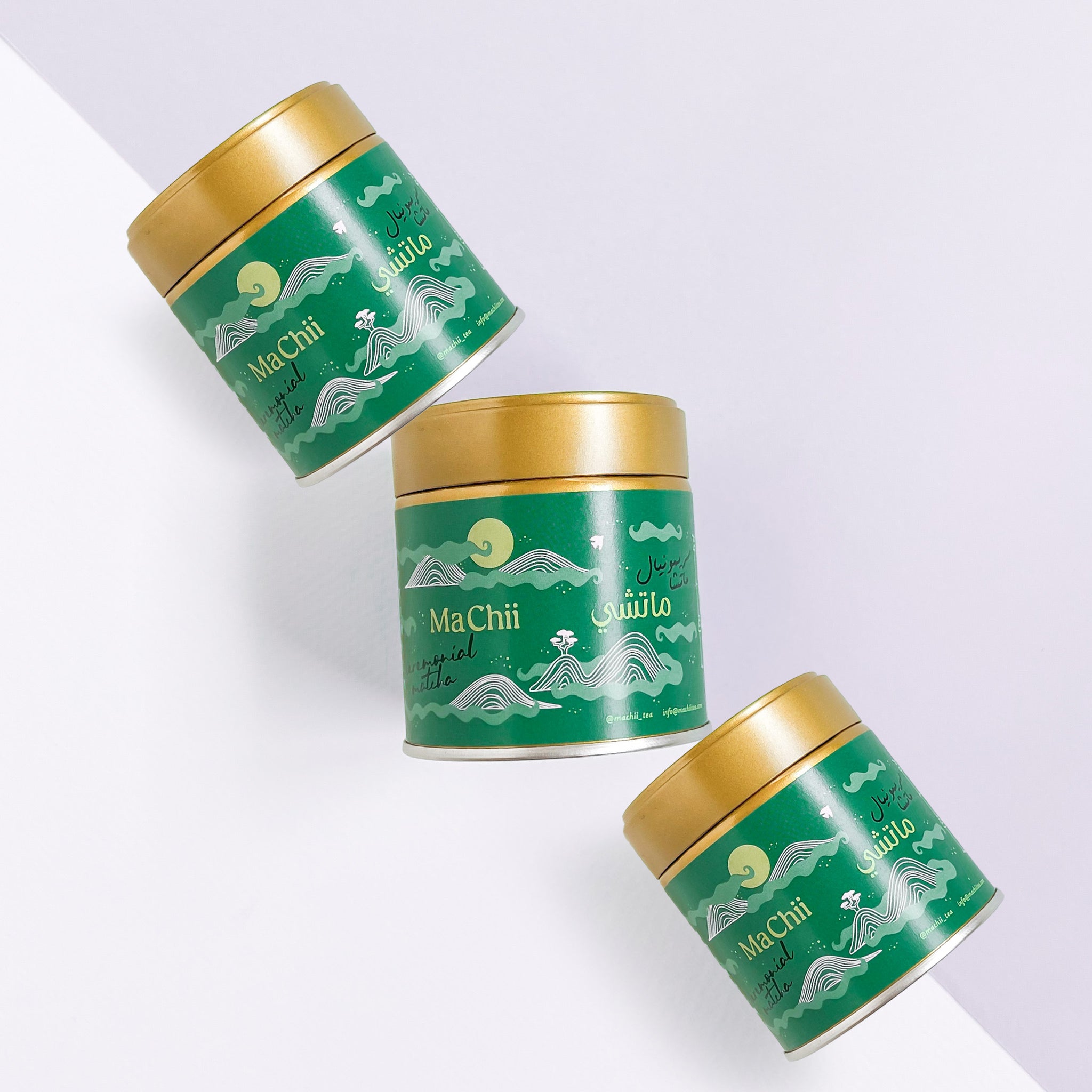 three ceremonial matcha for lattes organic tins on a table. the tins are all gold with green packaging of mountains.