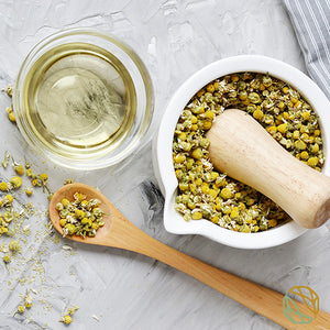 
                  
                    organic loose leaf chamomile tea spread out across the table. chamomile tea brewing in a cup next to the leaves
                  
                